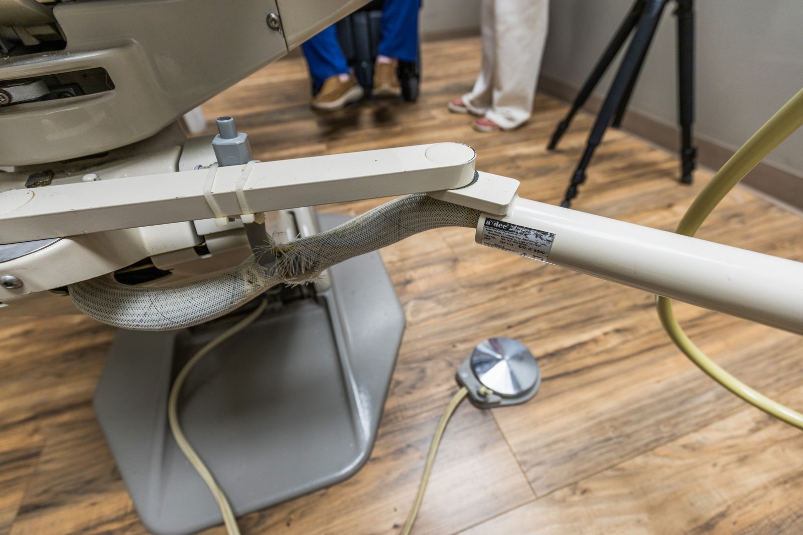 Camera on a tripod set up in a dental operatory, with crew working in the background